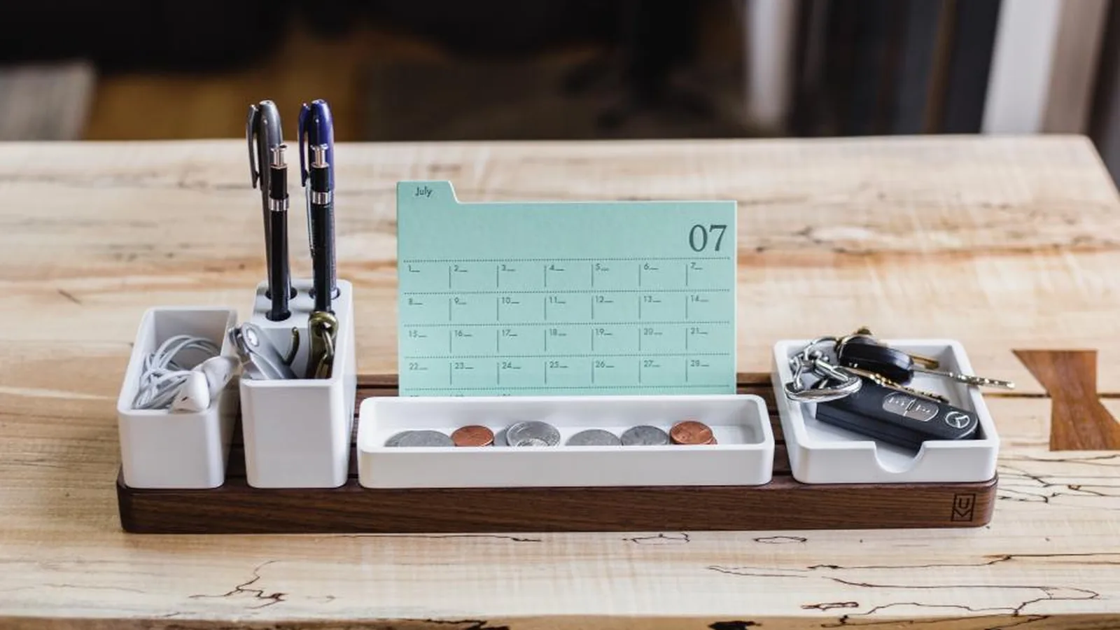 Calendário de mesa ao lado de canetas num organizador